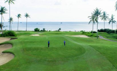 Golfer preparing to putt on the lush green course of Laguna Golf Bintan, surrounded by tropical beauty.