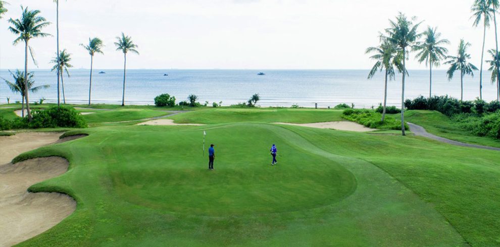 Golfer preparing to putt on the lush green course of Laguna Golf Bintan, surrounded by tropical beauty.
