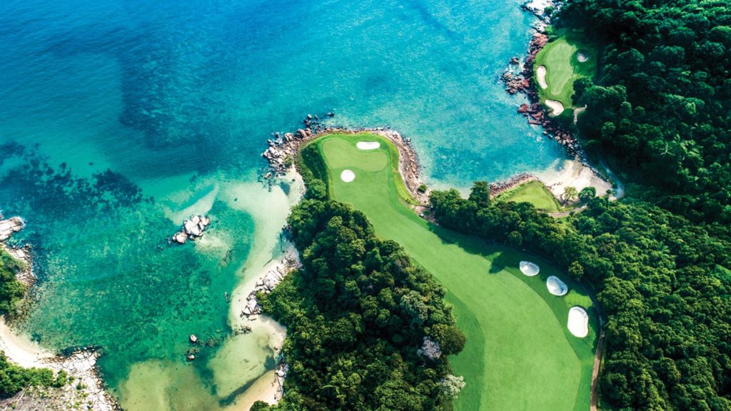 A golf cart on the scenic path surrounded by lush tropical greenery at Ria Bintan Golf Club